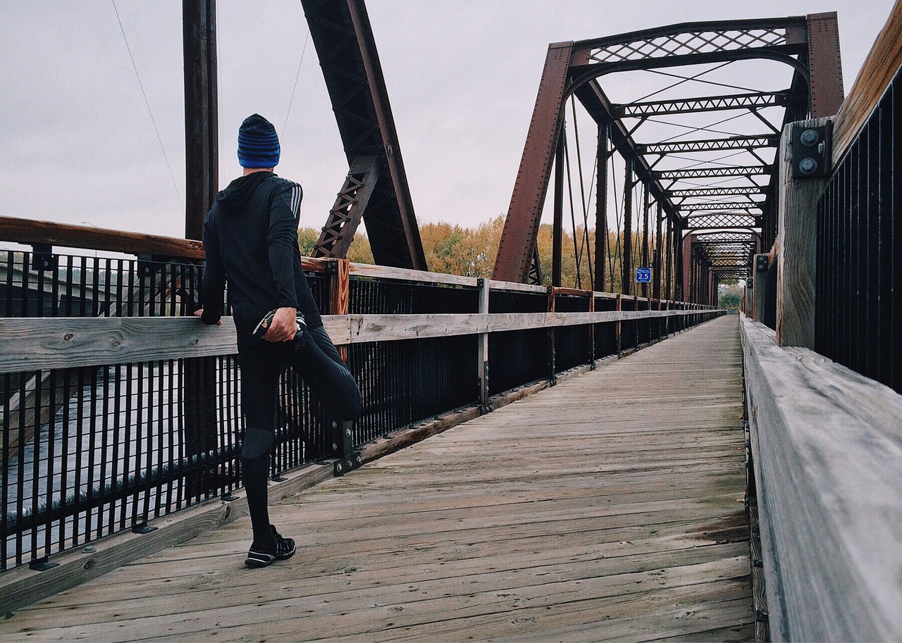 a person stretching in preparation for a run across a long bridge