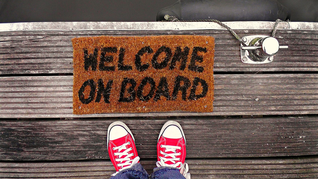 feet on the edge of a dock with a welcome mat that says welcome on board